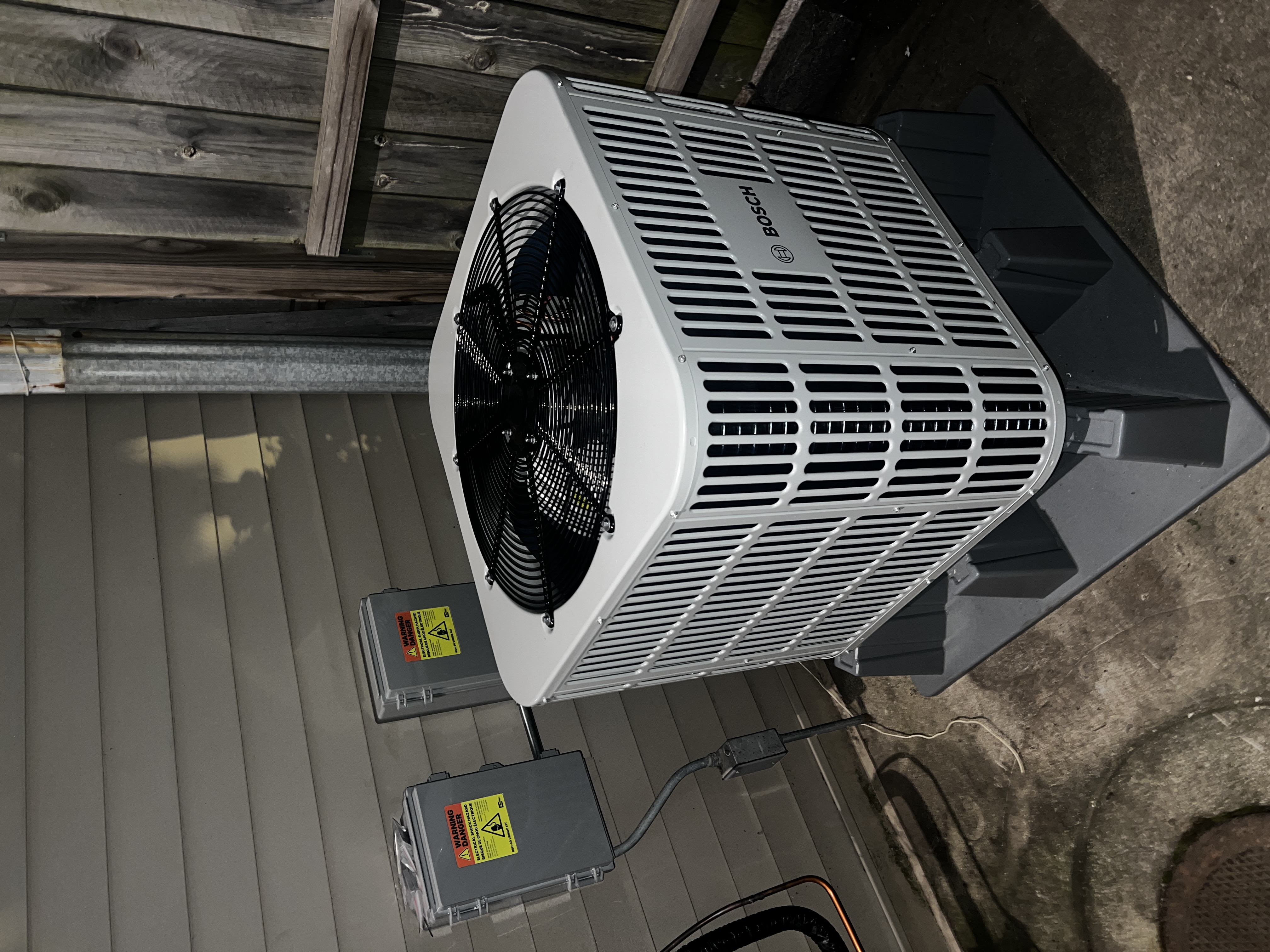 White Bosch condenser on a raised base beside a home