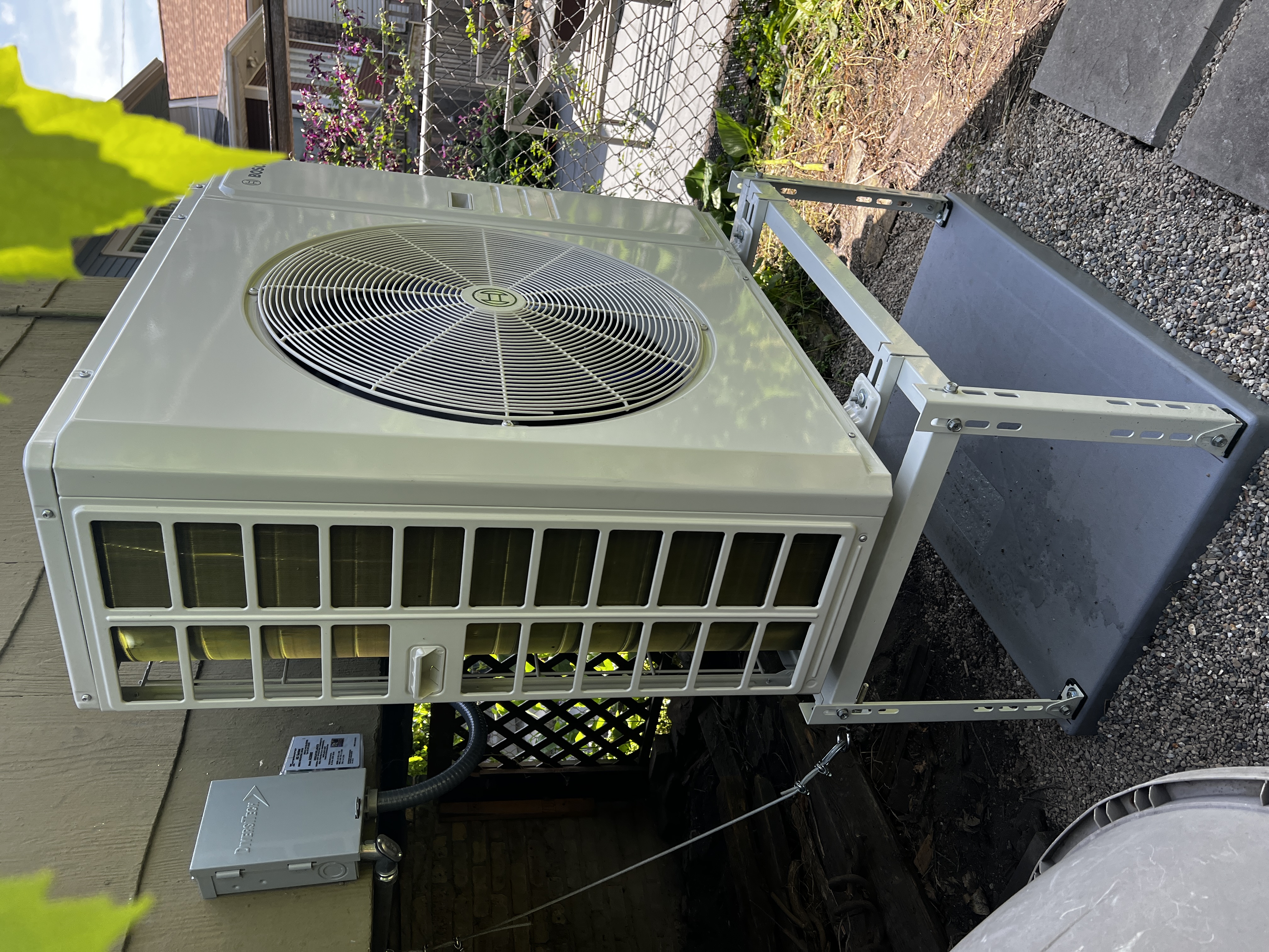 Bosch outdoor unit on an elevated metal stand and pad beside a home
