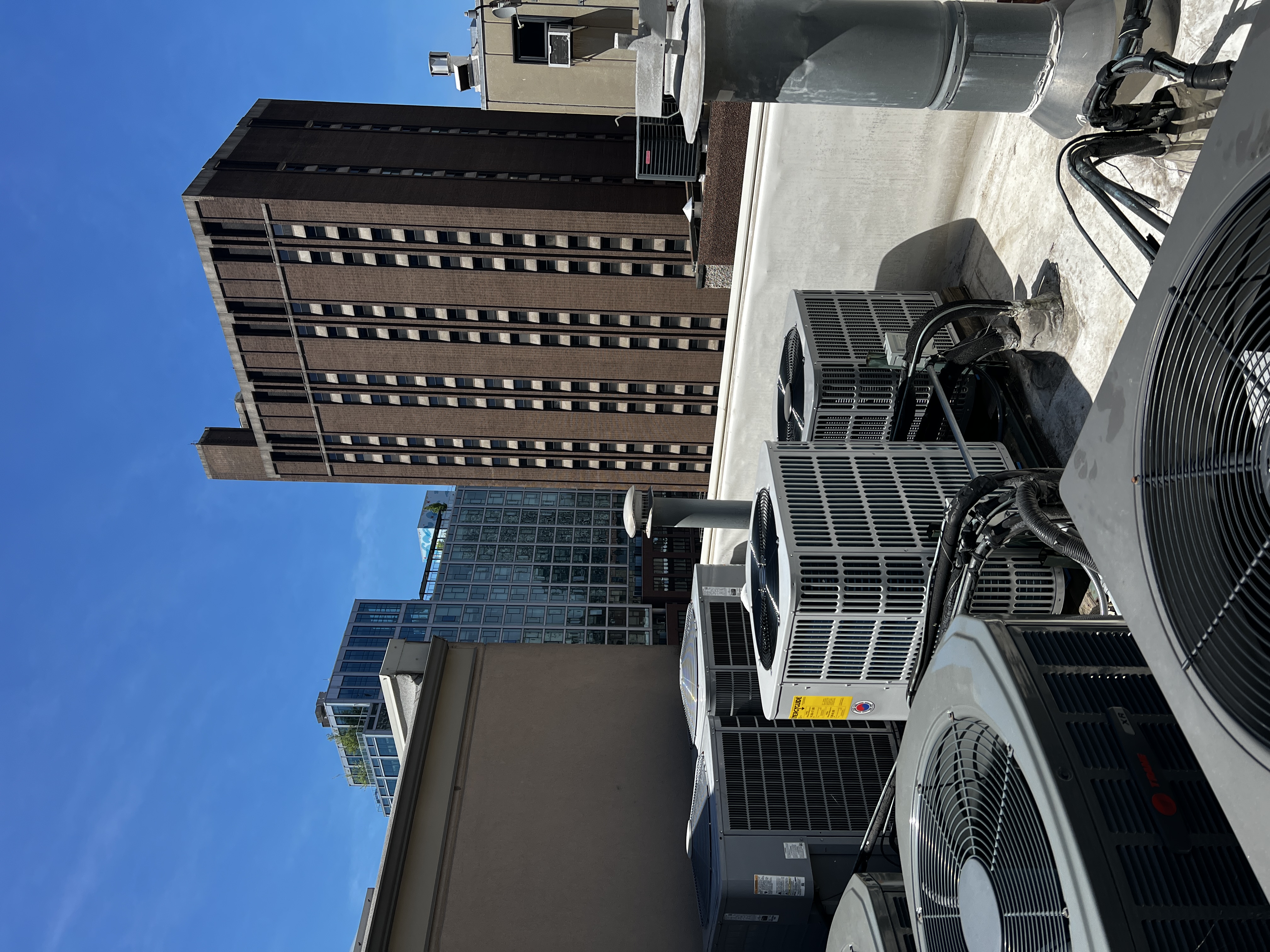 Outdoor condensers on a Chicago rooftop beneath a blue sky and city skyline
