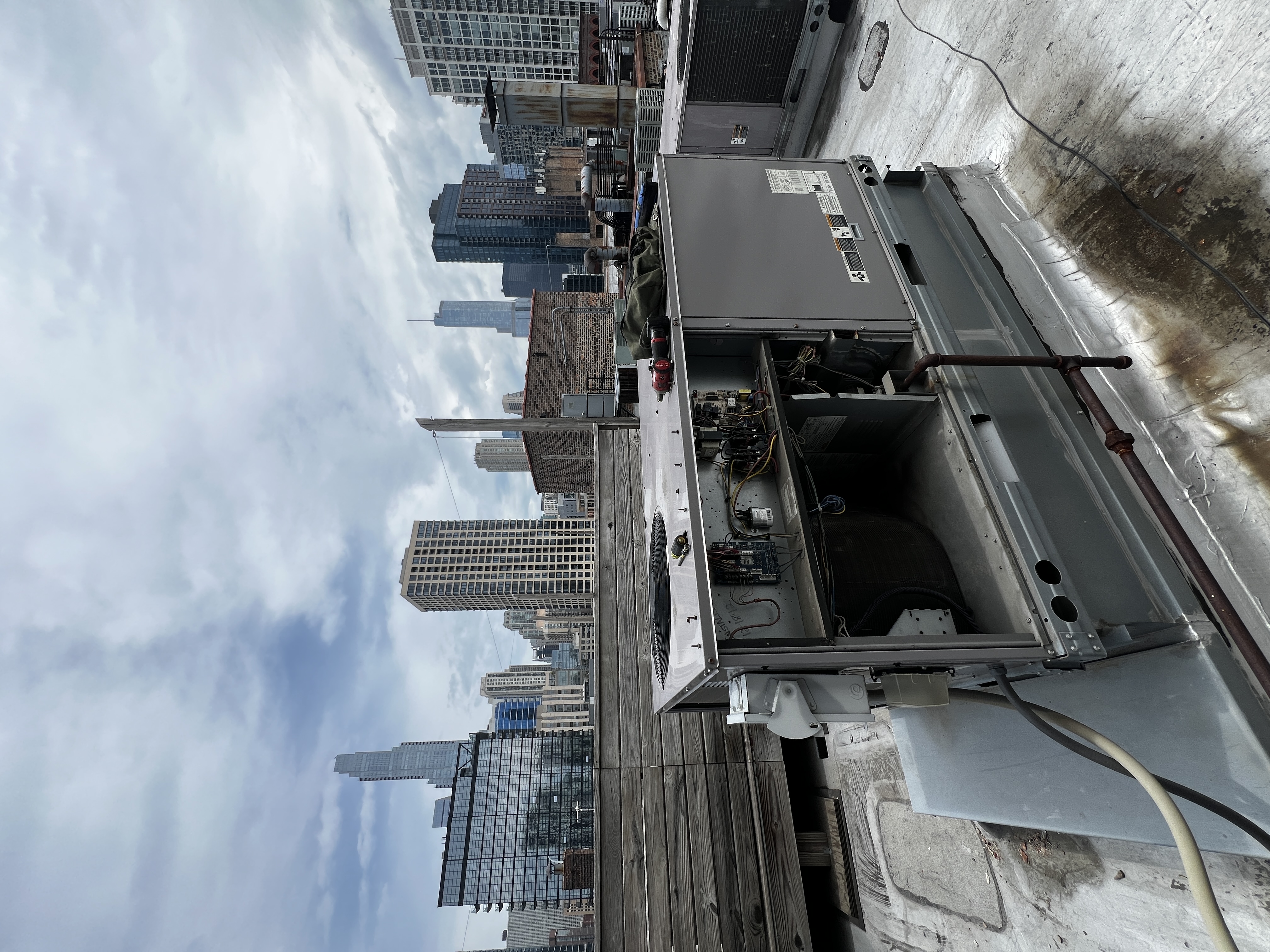 Rooftop HVAC unit with its service panels open against the Chicago skyline
